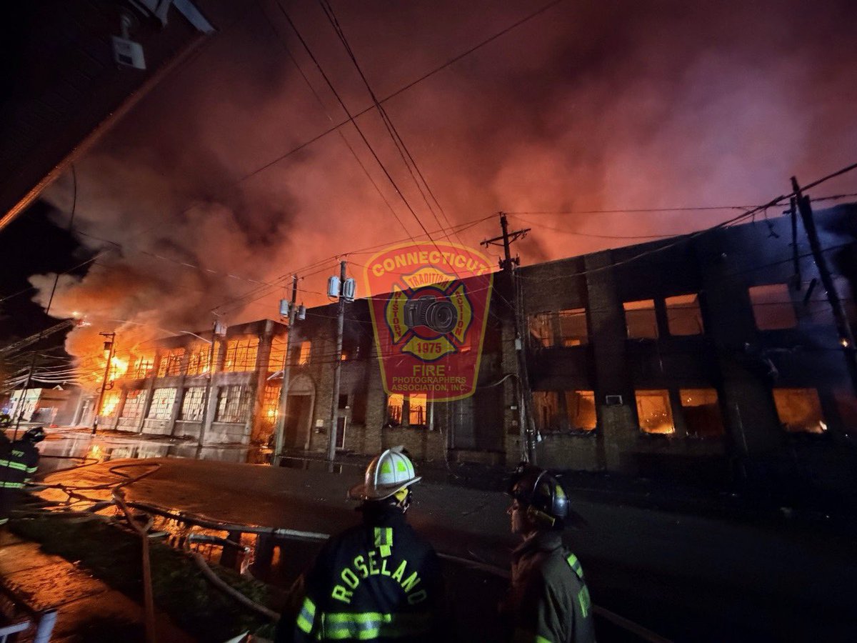CFPA Vice President Chris Clarke (@FirstDuePhotog) reports the 9 Alarm blaze continues to burn as crews are dealing with water supply issues